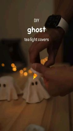 a person holding a tea light in their hand with ghost figurines behind them