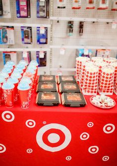 there is a red table with many cups on it and some candy in the middle