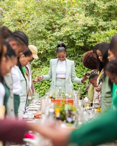 a group of people standing around a table with food and drinks on top of it