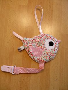 a pink and white bird shaped purse on top of a wooden floor next to a lanyard