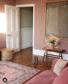 a living room filled with furniture and a painting hanging on the wall above a pink couch