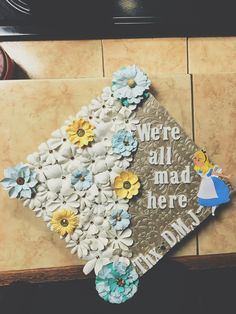 there is a graduation cap decorated with flowers on the top and words that read, we're all mad here