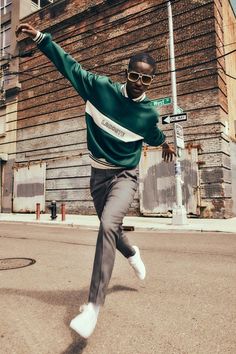 a man in green sweater and grey pants dancing on street