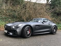 a grey mercedes sports car parked on the side of a road next to some bushes