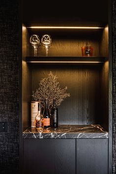 a shelf with bottles and candles on top of it in a room that has black walls