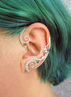 a woman with green hair wearing a pair of ear piercings in her left ear