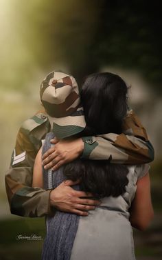 two people hugging each other while wearing camouflage clothing