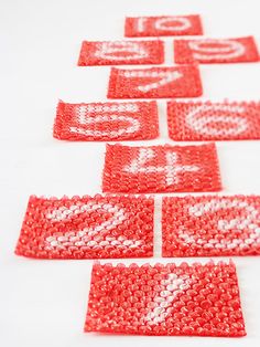 several pieces of beaded fabric with letters and numbers on them are laid out in rows