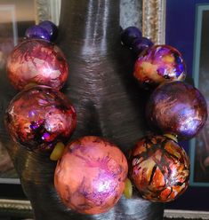 Despite their huge size (3" in front), these beads are light enough to float in water so you needn't have any concerns about neck strain. 32" in length. Each purple, gold, orange, yellow and pink bead is unique yet designed to complement one another. The front beads are spaced with recycled yellow African glass rondelles. Six smaller rich purple beads finish the back. Each bead is finished with a UV protectant to prevent the colors from fading. Closes with a lobster claw clasp. The quintessentia Artistic Beaded Necklace With Large Beads, Unique Large Glass Beads, Unique Faceted Beads For Festival, Unique Large Beads Necklace For Party, Purple Alcohol, Rocker Chic Accessories, Unique Pendant Necklace, Purple Beads, Chest Piece