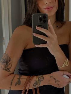 a woman taking a selfie with her cell phone in the mirror while wearing a black strapless dress