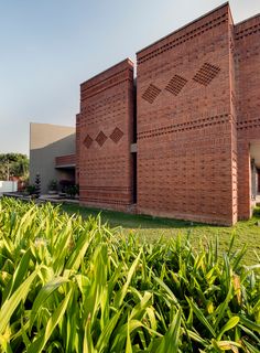 the building is made out of bricks and has green grass in front of it,