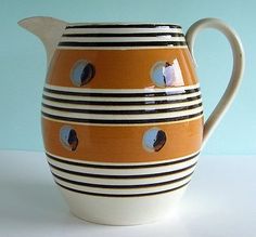 an orange and white striped pitcher with holes in the middle, on a light blue background