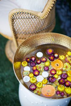 a bucket filled with lots of liquid next to a wicker chair on the grass