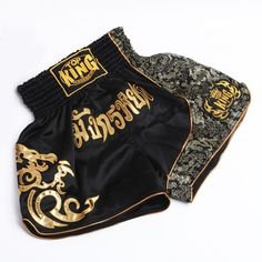 two black and gold boxing shorts sitting on top of each other, one with the word king written on it