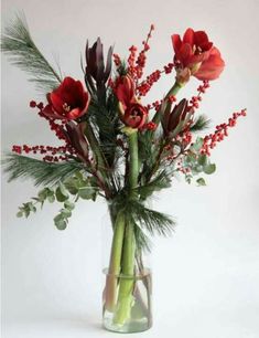 a vase filled with red flowers and greenery