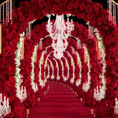 an elaborate red and white wedding arch with chandeliers, flowers and candles on it