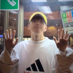 a young man wearing a yellow hat and holding his hands up in front of him