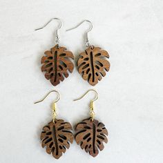 three pairs of wooden earrings with leaf designs on them, sitting on a white surface