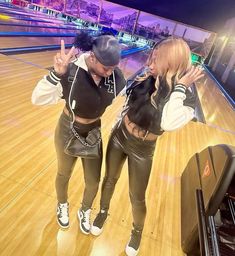 two women standing on top of a bowling court holding their hands up in the air