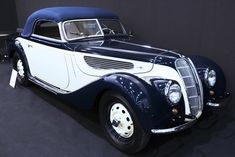 an old blue and white car is on display