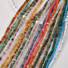 several strands of glass beads are displayed on a white surface with other beads in the background