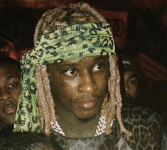 a man with dreadlocks and a green bandanna on his head is surrounded by other people