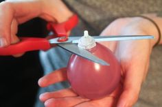 a person holding a pair of scissors cutting an egg with a pliers on it