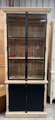 an old wooden cabinet with glass doors and pipes on the bottom, sitting in a warehouse