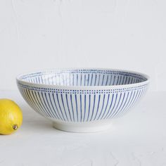 a blue and white striped bowl next to a lemon