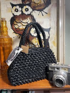 Lovely little black beaded bag, to spice up your wardrobe. Hand woven raffia and multi-faceted black beads, double arch handles and gold-tone accents. sits on four little metal feet. Stands about 7" tall and 9" wide. In very good shape! Retro Black Handmade Shoulder Bag, Black Handmade Retro Shoulder Bag, Handmade Black Retro Shoulder Bag, Traditional Black Woven Crochet Bag, Traditional Brown Beaded Bag, Vintage Beaded Shoulder Bag, Vintage Beaded Clutch Bag, Vintage Black Beaded Evening Bag, Woven Raffia