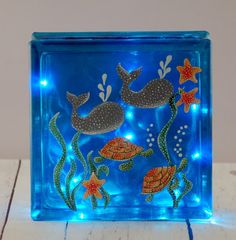 a blue glass block with sea animals and fish on it, sitting on a wooden table