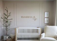 a baby's room with a white crib, chair and potted plant