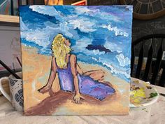 a painting of a woman sitting on the beach