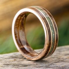 a wooden ring with two different wood inlays sitting on top of a piece of wood