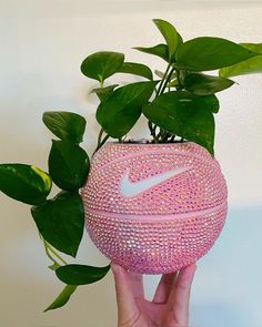 a hand holding a pink nike ball planter