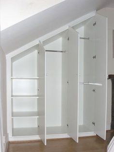 an empty white closet in the corner of a room next to a bed and fireplace