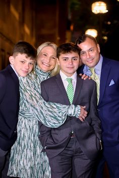 two men and a woman posing for a photo with a young boy in a suit