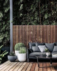 a couch and table on a wooden deck with trees in the backgrounnd