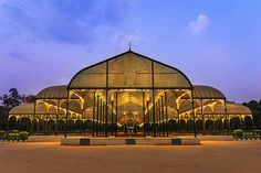 a large glass building with lights on it's sides and columns in the middle