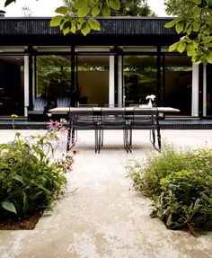 a table and chairs in front of a house with large glass doors on the outside