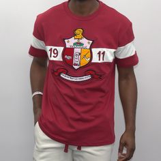 Experience the true essence of style with this Crimson T-Shirt from Kappa Alpha Psi Shield. Immerse yourself into a world of elegance and sophistication with its vibrant crimson color. This T-Shirt is a must-have for every stylish man out there as it adds an extra edge to your wardrobe. The Kappa Alpha Psi Shield logo on the shirt showcases your inner strength and vigor. Wear it comfortably to any occasion and let your personality speak for itself. Fast Shipping & Processing: 1-2 days to process Collegiate Crew Neck Top With Embroidered Logo, Varsity Cotton T-shirt With Embroidered Graphics, Collegiate Crew Neck Top With Embroidered Graphics, Varsity Crew Neck Tops With Embroidered Graphics, Graphic Tee With Embroidered Graphics For College, Collegiate Cotton T-shirt With Embroidered Graphics, Collegiate Embroidered Crew Neck T-shirts, Varsity Style Cotton Tops With Embroidered Graphics, Cotton Varsity Tops With Embroidered Graphics