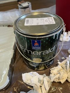 a can of white paint sitting on top of a table next to some toilet paper