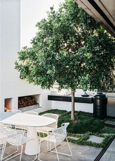 a white table and chairs sitting under a tree in the middle of a patio area