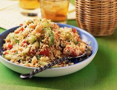 a bowl filled with rice and vegetables on top of a table next to two glasses