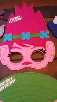 a pink mask with blue flowers on it sitting on top of a wooden table next to other items