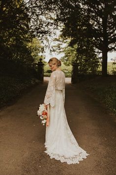 Bride in boho Lace Wedding Dress with flute sleeves holding a colourful bouquet