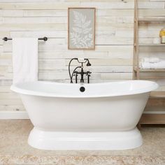 a white bath tub sitting in a bathroom next to a wooden shelf filled with towels