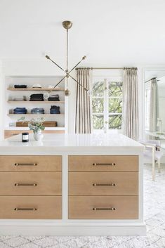 a kitchen with an island and white countertops in the center, along with open shelving