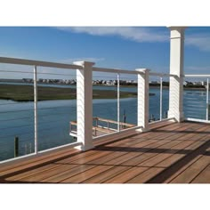 a wooden deck with white railings next to the water