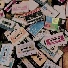 a pile of cassettes sitting on top of a wooden table next to each other